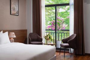 a hotel room with a bed and two chairs and a window at Marina Hotel Bac Giang in Hoa Yên