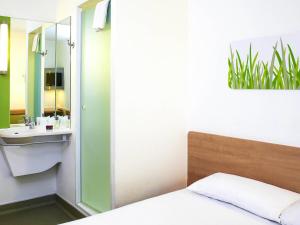 a bedroom with a bed and a sink and a mirror at ibis budget Birmingham Airport Terminal Building - NEC in Bickenhill