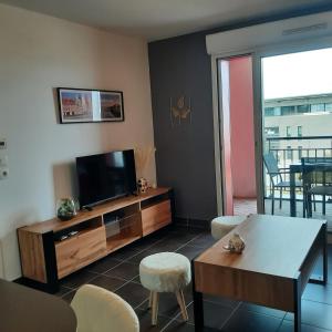 un salon avec une télévision, une table et des chaises dans l'établissement Le Patio Arena, classé 2 étoiles, terrasse, parking, wifi, local vélos, à Bayonne