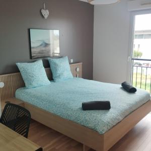 une chambre avec un lit avec des oreillers bleus dans l'établissement Le Patio Arena, classé 2 étoiles, terrasse, parking, wifi, local vélos, à Bayonne