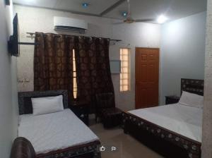 a bedroom with two beds and a chair and a window at Hotel New Garden in Dargai