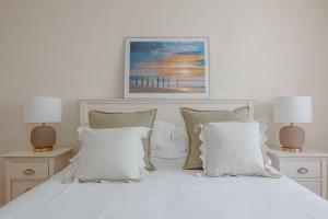 ein weißes Bett mit Kissen und einem Bild von einem Pier in der Unterkunft Sea Breeze in Ulwell