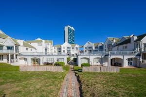 a row of houses with a tall building in the background at Ocean Whisper At 42 in Gqeberha