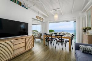 a living room with a television and a table with chairs at Ocean Whisper At 42 in Gqeberha