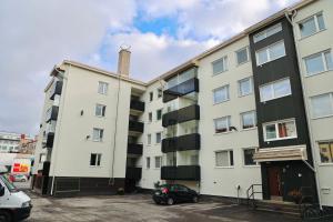 un immeuble d'appartements avec une voiture garée sur un parking dans l'établissement Aurora Central Suite III By BookLapland, à Rovaniemi