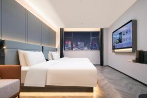 a hotel room with a white bed and a tv at Atour S Hotel Ningbo Heyi Avenue in Ningbo