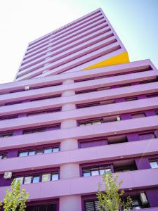 a tall pink building with a yellow stripe on it at Blush Studio at Rose in Prishtinë