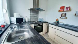 a kitchen with a sink and a microwave at L'Echappée Quéantaise, Parking, Jardin, au calme  +20 photos