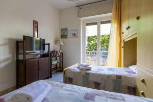 a bedroom with two beds and a tv and a window at La casa di Sara in Cipressa
