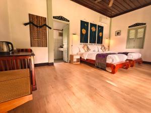 a bedroom with two beds and a wooden floor at Luang Prabang chanon hotel in Luang Prabang
