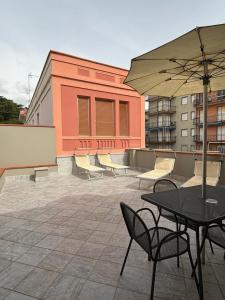 a patio with a table and chairs and an umbrella at Hotel Delle Rose in San Bartolomeo al Mare +97 photos