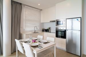 cocina con mesa blanca, sillas y nevera en Sea View 2-Bed Apt Walk to Beach - KBR35, en Ban Bang Po