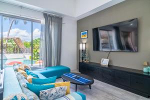 Tropical 3 Bed Pool Villa in Plai Laem - KBR42 في Plai Laem: غرفة معيشة مع أريكة زرقاء وتلفزيون بشاشة مسطحة