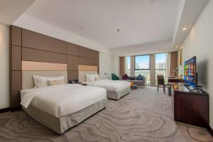 花都にあるZhengsheng Honggu Hotel - Guangzhou Sunac Cultural Tourism City Huadu Plazaのベッド2台とテレビがあるホテルの部屋
