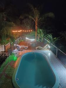 a swimming pool at night with chairs and tables at Suite Térrea in Bombinhas