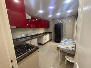 una cocina con armarios rojos y una mesa. en California E, en Kenitra