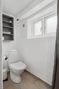a white bathroom with a toilet and a window at FY385-Nyborg-Kronprinsensgade-1-st in Nyborg +18 photos