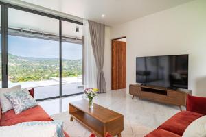 a living room with a large television and a red couch at New 3BR Pool Villa in Bophut - KBR46 in Bang Rak Beach