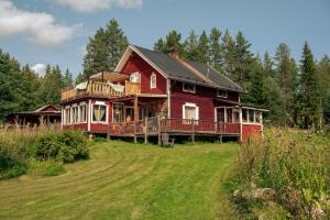 a large red house on top of a field at Wildlife Appartement - Wilderness Adventures Sweden in Bispgården