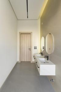 a white bathroom with two sinks and a mirror at شالية فيلا ألور عقدة in ‘Iqdah