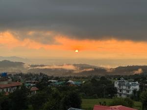 una puesta de sol sobre una ciudad con el sol en el cielo en TLO - The Life Outdoor, Bir Billing, en Bīr