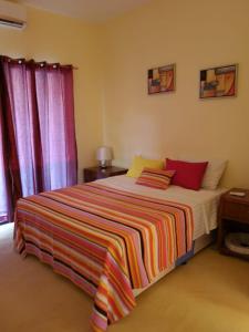 1 dormitorio con 1 cama con una manta a rayas de colores en Silva house bilene, en Vila Praia Do Bilene