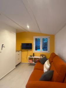 a living room with an orange couch and a tv at Studio Smart&Cosy in Porto-Vecchio