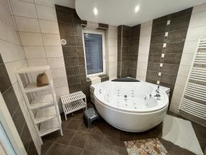 a large white tub in a bathroom with a window at Panoráma Apartman in Miskolc +45 photos