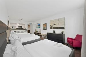 Una habitación de hotel con dos camas y una silla roja. en Casa Grande Suites on Ocean Drive, en Miami Beach
