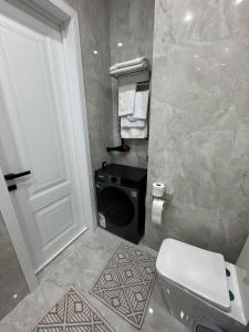 a bathroom with a toilet and a washing machine at Stylish apartment & Perfect choice for Travellers in Almaty
