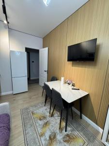 a dining room with a table and a tv on a wall at Stylish apartment & Perfect choice for Travellers in Almaty