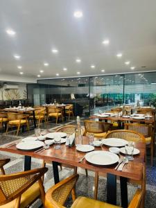 une salle à manger avec des tables et des chaises en bois avec des assiettes et des verres dans l'établissement Royal Studio Golf course road - Gurugram, à Gurgaon