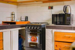 Il comprend une cuisine équipée d'un four et d'une dinde. dans l'établissement Culture House - Heritage Stay with Family Comforts, à Gulu