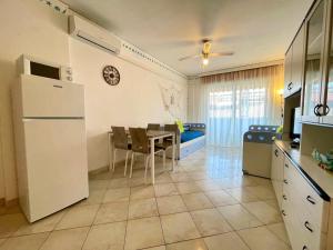 a kitchen with a table and a white refrigerator at Lovely flat with sunny terrace in Porto Santa Margherita di Caorle