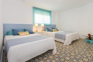 two beds in a room with blue and white at Exclusivo apartamento con piscina privada junto a la playa in Gandía