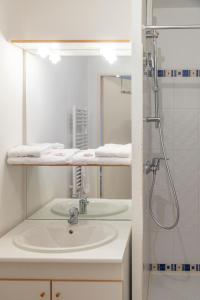 Un baño blanco con lavabo y ducha. en Well-equipped studio with balcony, en Séné