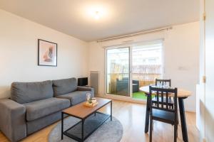 una sala de estar con un sofá y una mesa en Well-equipped studio with balcony, en Séné
