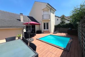 a swimming pool with an umbrella and a house at Villa familiale piscine proche de Paris in Antony