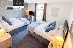a bedroom with two beds with pillows and a tv at Modern 3BDR House By Properties With Joy Short Lets Manchester Perfect For Contractors & Large Groups With Free WiFi & Parking in Ashton under Lyne +18 photos