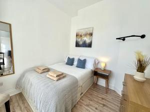 a white bedroom with a bed with blue pillows at The Tay Residence, City Centre in Perth