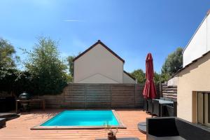 a swimming pool in front of a building with a red umbrella at Villa familiale piscine proche de Paris in Antony
