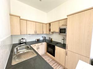 a kitchen with wooden cabinets and a sink at The Tay Residence, City Centre in Perth