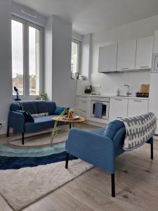 a living room with two blue couches and a kitchen at Quiet duplex in historic town centre in Perros-Guirec