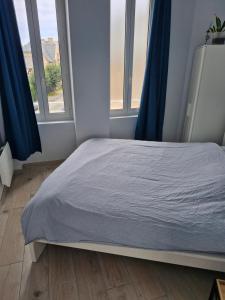 a bed in a room with two windows at Quiet duplex in historic town centre in Perros-Guirec