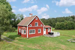 a red barn on a grassy field with trees at JON388-Stockaryd-Hetseryd in Södra Hetseryd