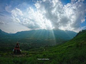 a view of a mountain with the sun shining through the clouds at prince's place cabins and camping in Badulla +17 photos