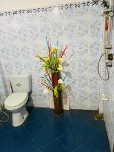 a bathroom with a toilet and a vase of flowers at Shalom place in Bandarawela