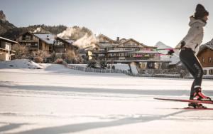 a person on skis in the snow with houses in the background at Wellnesshotel Der Engel - Tannheimer Tal in Grän