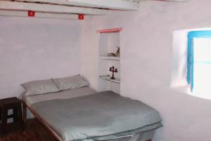 a small white room with a bed and a cross on the window at Mount Holiday Pahadi Home Stay in Gupta Kāshi