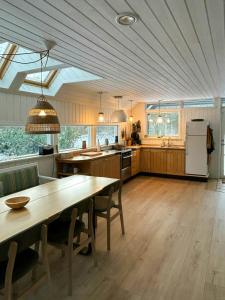 a large kitchen with a wooden table and a dining room at Hidden Gem By Thy National Park in Bedsted